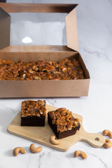 The square slice of toffee cake with cashew nut
and caramel syrup on marble background. 