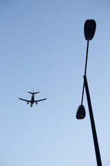 Vertical shot of aeroplane flying overhead with a lamppost in the foreground