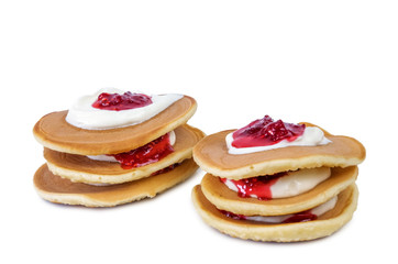 Stacks of pancakes with sour cream and raspberry jam isolated on white background