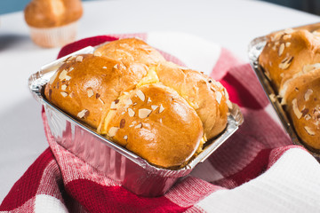 Fresh and shiny Brioche bread in a aluminium food packaging, checkered pattern table cloth.
