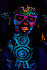 portrait of cool african man with fluorescent body art dancing isolated in dark space. dj man perform dance, mysterious dancer with colorful prints on face and body