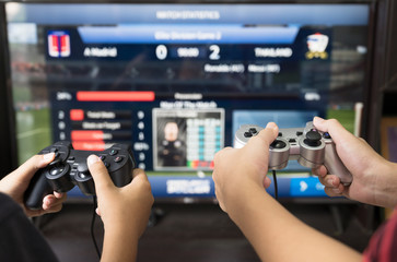 Gamer hand playing video game  at home.Boy friends group enjoy and relax with football game online on TV.Stay at home concept.