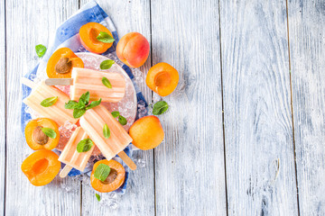 Homemade apricot popsicles, fruity lollypop non-dairy vegan apricot gelato, on grey old wooden background copy space top view