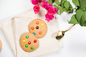 Homemade cookies with chocolate candy on top, served on a napkin with a gold spoon. Very colorful.
