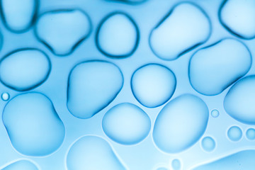 Image from microscopy of water drops in the microscopic slide.Abstract oxygen bubbles in the water.Mixed and different shape background in the blue tone.