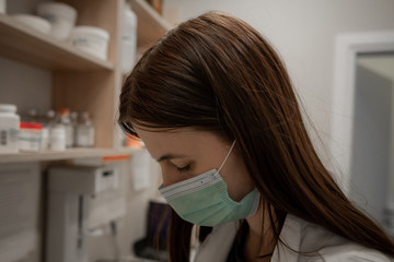 Closeup shot of tired pharmacist working during a coronavirus pandemic and wearing an anti-virus mask. Pharmacist looking for a medicines.