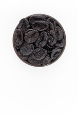Dried plumps in round bowl on white background, top view