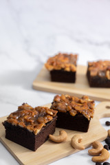 The square slice of toffee cake with cashew nut and caramel syrup on marble background.