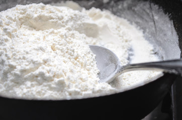 Fototapeta na wymiar Cooking halva in a frying pan. Flour in a pan with a spoon