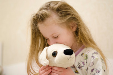the girl hugged and pressed a soft toy to a dog in the room, closed her eyes