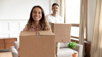 Portrait happy young couple holding cardboard boxes with belongings, moving into new first house,...