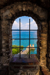 Sirmione seen through a grate window in the scaligero castel, a beautiful medieval picture of sea and land on the Garda Lake