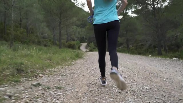 Chica joven atractiva corre por la monta&ntilde;a en un d&iacute;a nublado.