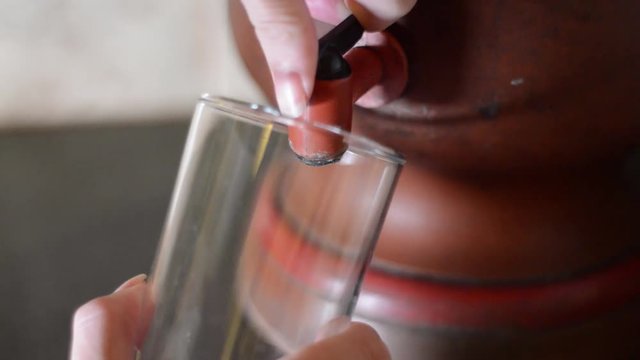person filling glass of water in old Ceramic clay filter, typical Brazilian way of filtering water