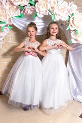 Two adorable girls on holiday show hearts with hands.