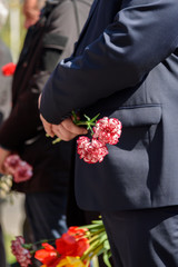 A bouquet of red carnations in the hands of a man in a suit, focus on the flower.