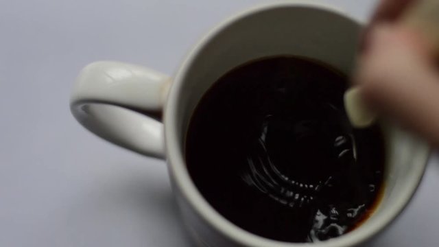 woman's hand mixing coffee with a spoon, beautiful bubbles and natural morning light