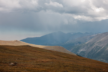 Obraz na płótnie Canvas Rain from the overhead storm clouds descends upon the distant mountains as viewed from atop Trail Ridge Road in Rocky Mountain National Park, Colorado in late August