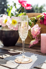 Champaign on a wooden table in the sun with flowers and candles
