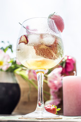 Cocktail on a wooden table in the sun with flowers and candles