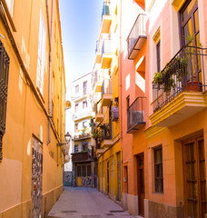 Fototapeta na wymiar Calle estrecha con las fachadas naranjas muy iluminadas en Valencia, España