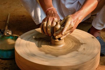 Pottery - skilled hands of potter shaping the clay on potter wheel making small bottle. Pot throwing. Manufacturing traditional handicraft Indian jar, pot, jug. Shilpgram, Udaipur, Rajasthan, India