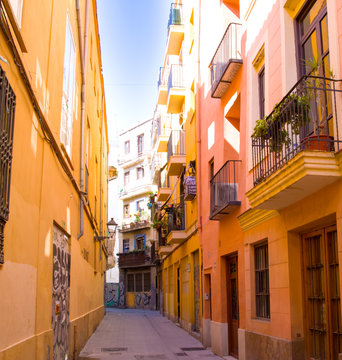 Calle estrecha con las fachadas naranjas muy iluminadas en Valencia, Espa&ntilde;a