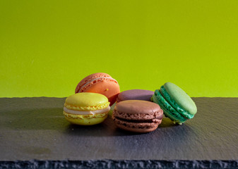 Home made still life with green plain background and coloured macaroons