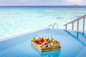 Breakfast in swimming pool, floating breakfast in tropical resort. Table relaxing in calm pool water, healthy breakfast and fruit plate by resort pool. Exotic summer diet luxury island beach lifestyle