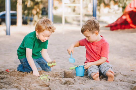 Two Caucasian Children Sitting In Sandbox Playing With Beach Toys. Little Boys Friends Having Fun Together On A Playground. Summer Outdoor Activity For Kids. Leisure Time Lifestyle Childhood.