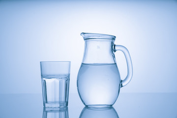 Pitcher with drinking water and a glass with a drink, blue tone
