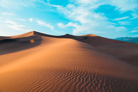 Three dunes at sunset across a vast expanse of sand