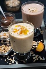 milkshakes with chocolate, oatmeal and mango in glasses, vertical top view