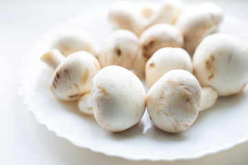 Fototapeta na wymiar champignon mushrooms lie on a white plate, blurred background