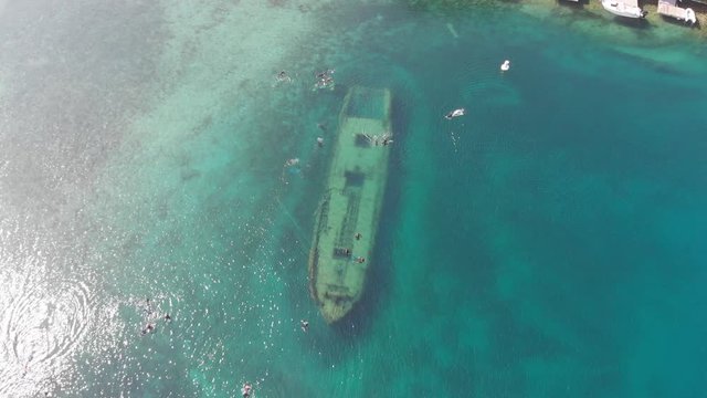 An aerial footage of People swimming over a shipwreck