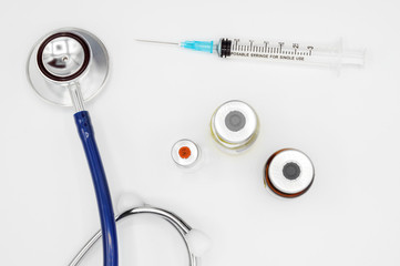 Medical equipment on doctor's desk, stethoscope ampules and syringe on white background with copy...
