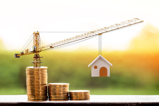 Stacking gold coins with increase and tower crane and hoist brake solutions with build new house in the public park, saving money and loan for construction real estate and home concept.