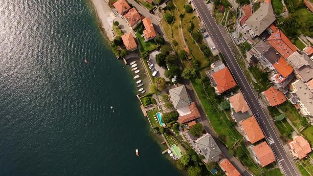 Top view of villa Teodolinda on shores of blue lake of Como in Italy in the village of Laglio. Motor boats sail past this charming place with ship pier and an outdoor pool. Drone shooting in a circle