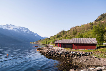 Red wooden houses by the water. North of Hardangervidda Park. Norwegian mountains.