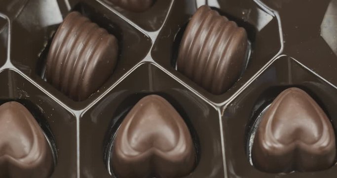 Woman chooses chocolate candy out of the box, tasty dessert background. Take one chocolate from a box of different candies.