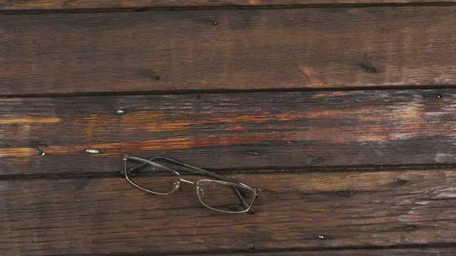 Modern spectacles lie on the old wooden surface. Zoom.