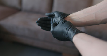 man hands takes off black nitrile protective gloves indoors