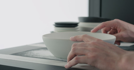 man hands sand bottom of white ceramic bowl