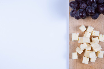 pieces of cheese and grapes on a plate on a table