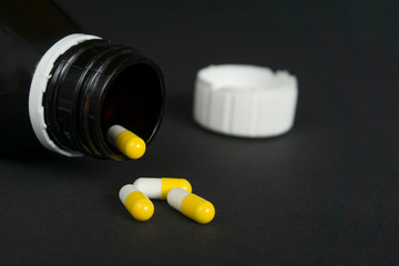 bottle with white-yellow  pills on black background with copy space