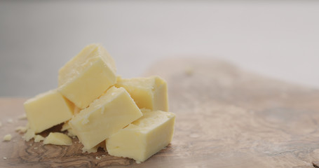 cheddar cheese in cubes on olive wood board