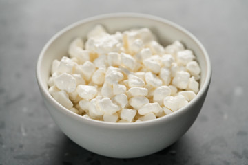 Cottage cheese in white bowl on concrete background