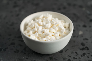 Cottage cheese in white bowl on concrete background