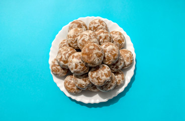 Famous russian gingerbread on white plate on blue background. Heap of round russian glazed gingerbread. Honey cakes. Top view