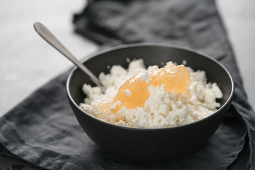 Cottage cheese with orange jam in white bowl on concrete background
